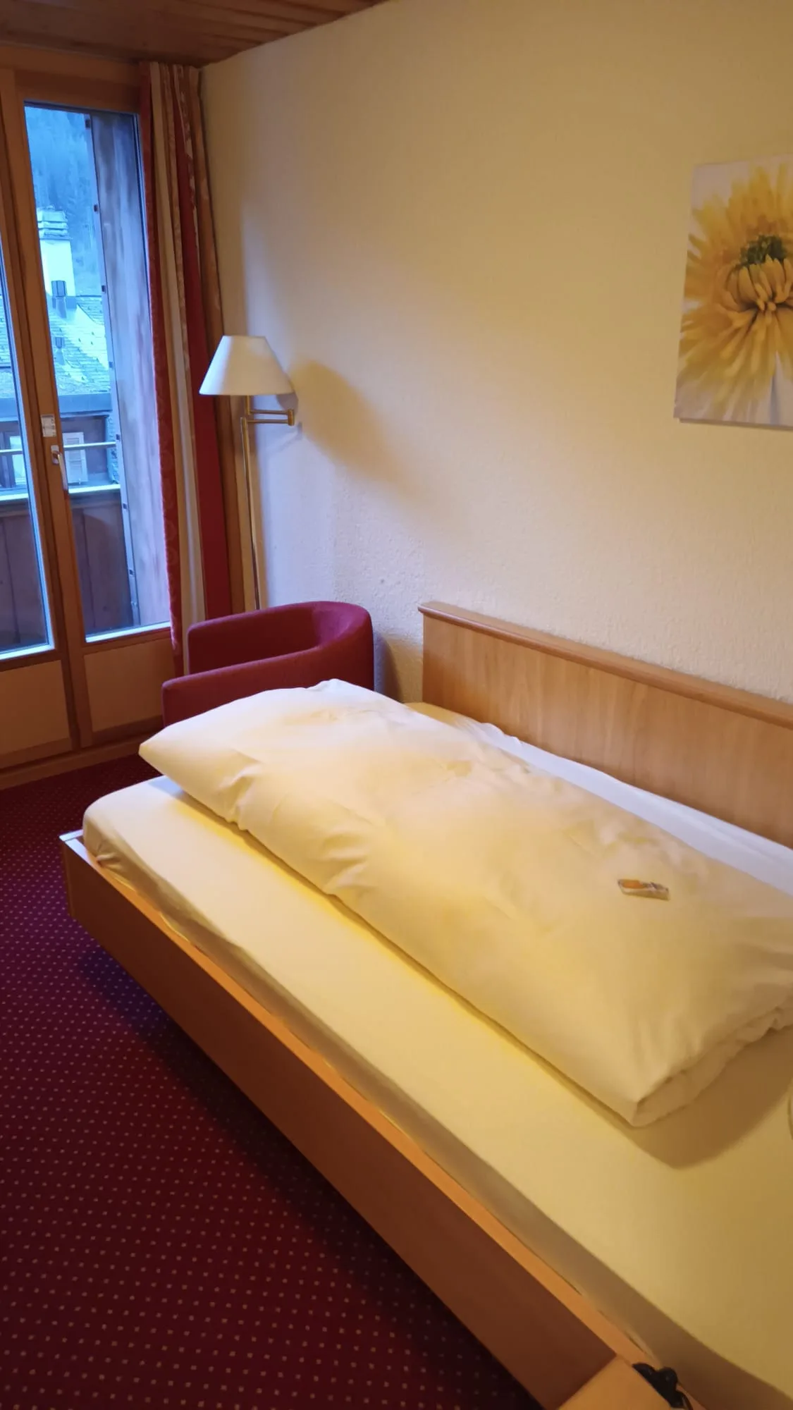 Hotelzimmer mit Einzelbett und Sonnenblumenbild an der Wand