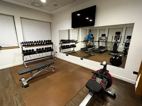 Fitnessraum mit Trainingsgeräten und Spiegeln