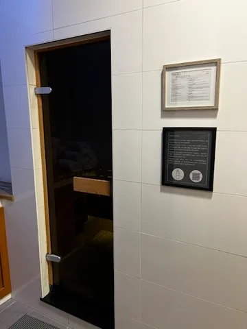 Sauna mit Holztür und Informationstafel an der Wand
