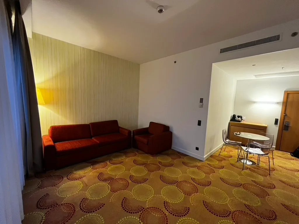 Hotelzimmer mit rotem Sofa und Sessel in warmen Farben
