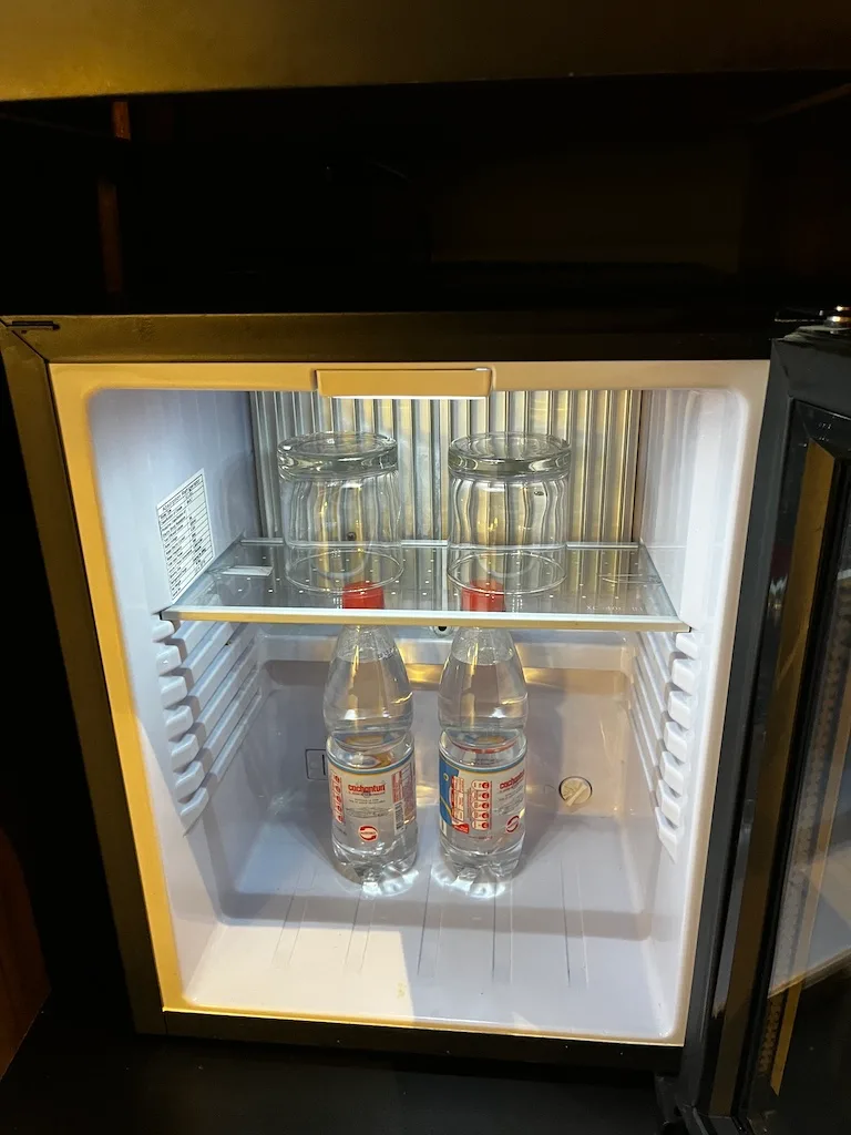 Hotelkühlschrank mit Mineralwasserflaschen und Gläsern