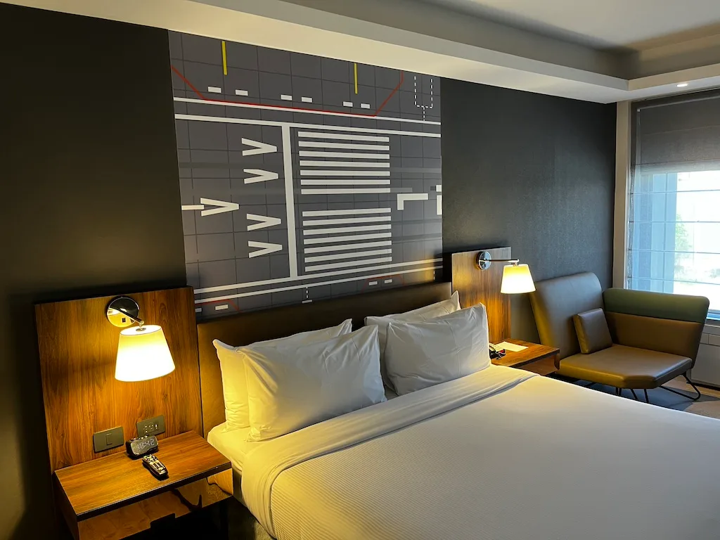 Hotelzimmer mit Doppelbett und Flughafensymbolwand
