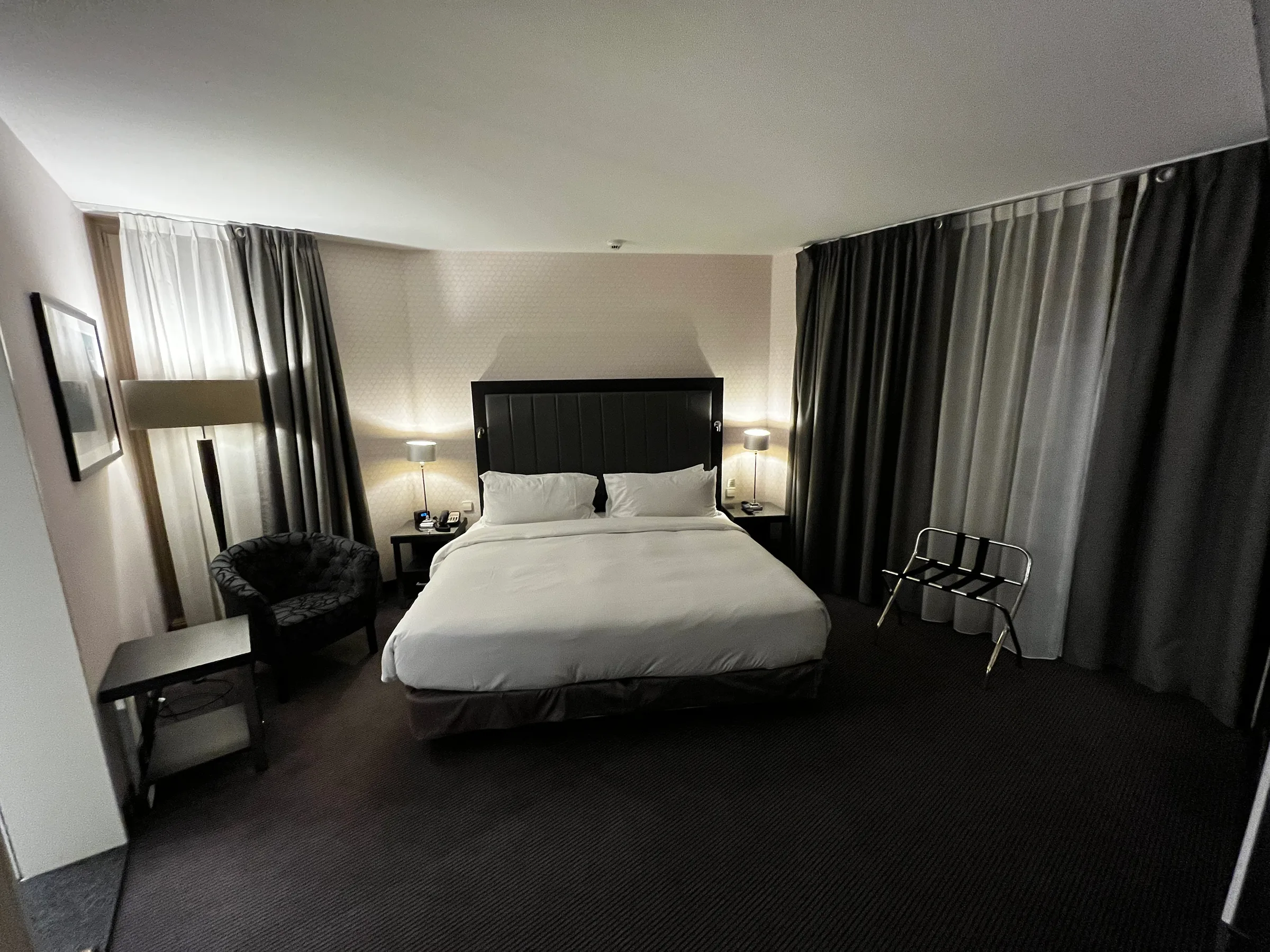 Hotelzimmer mit Doppelbett und grauen Vorhängen