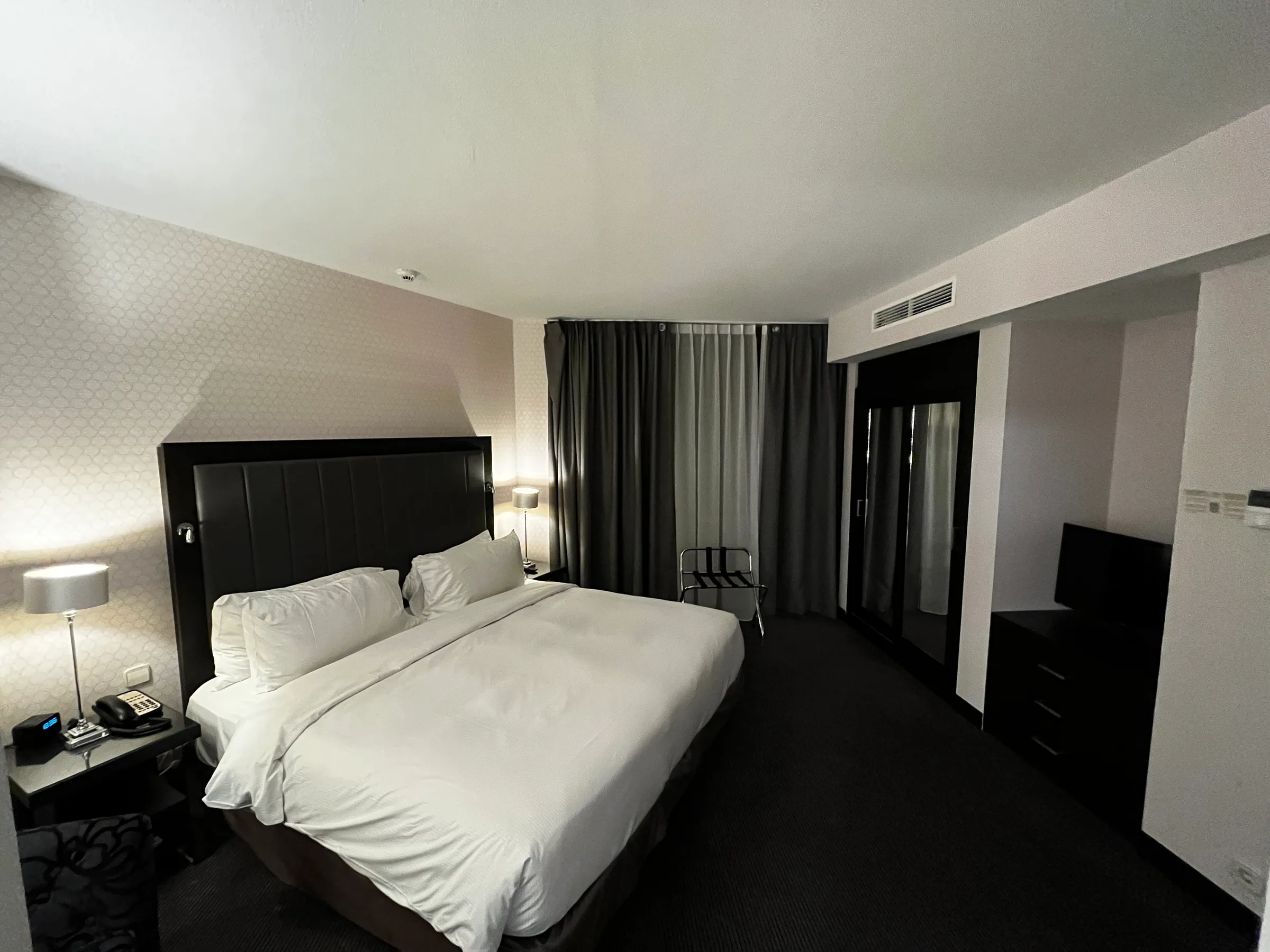 Hotelzimmer mit Doppelbett und grauem Vorhang