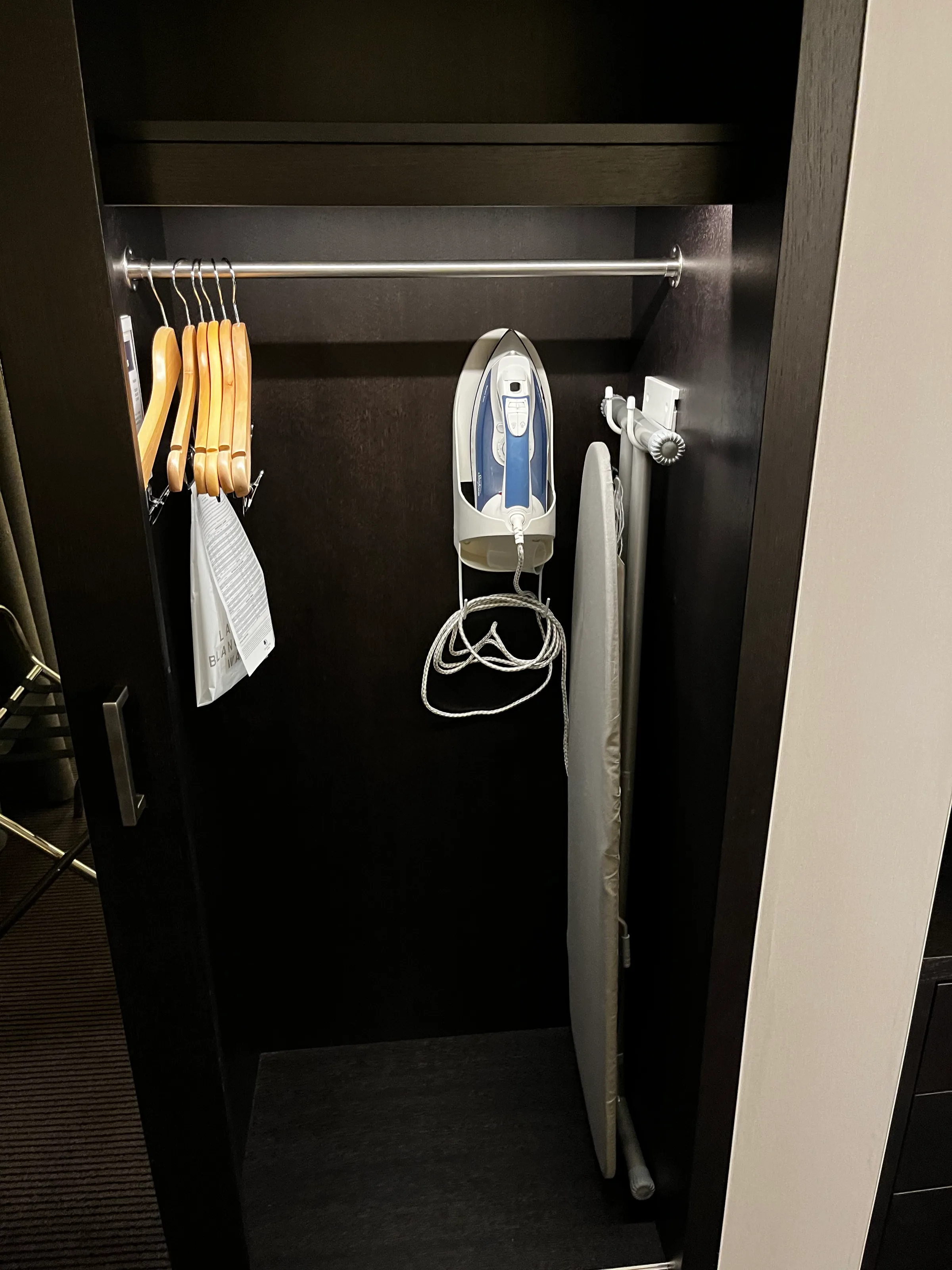 Schrank mit Bügeln und Bügeleisen im Hotelzimmer