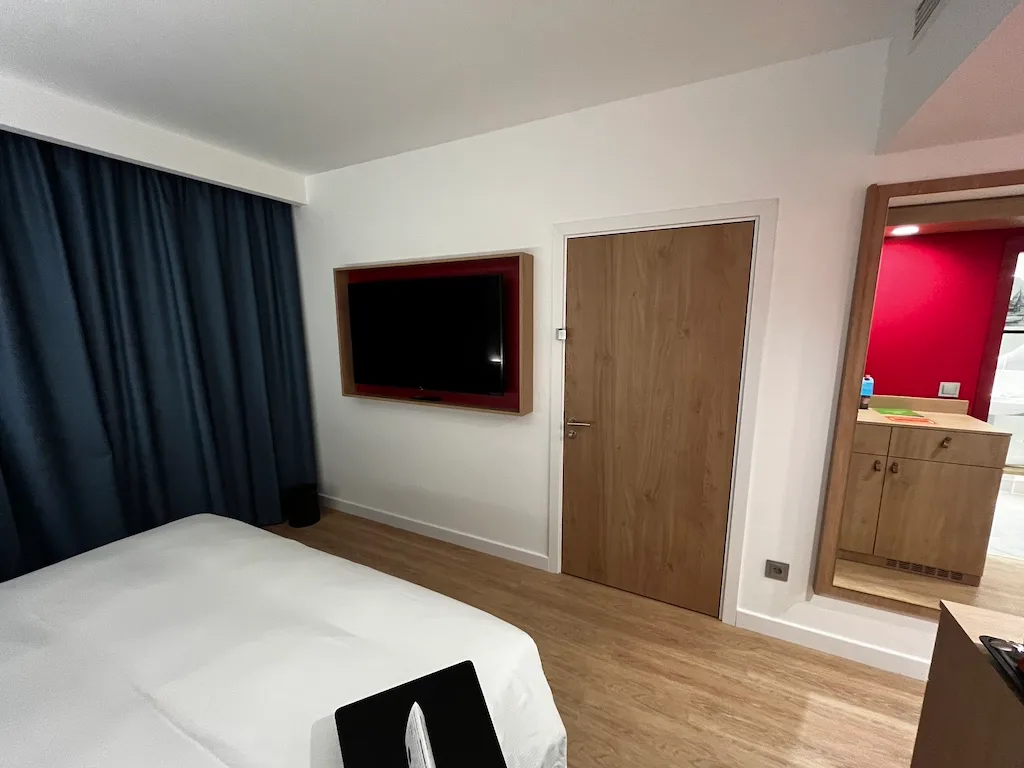 Hotelzimmer mit Doppelbett und Flachbildfernseher an der Wand