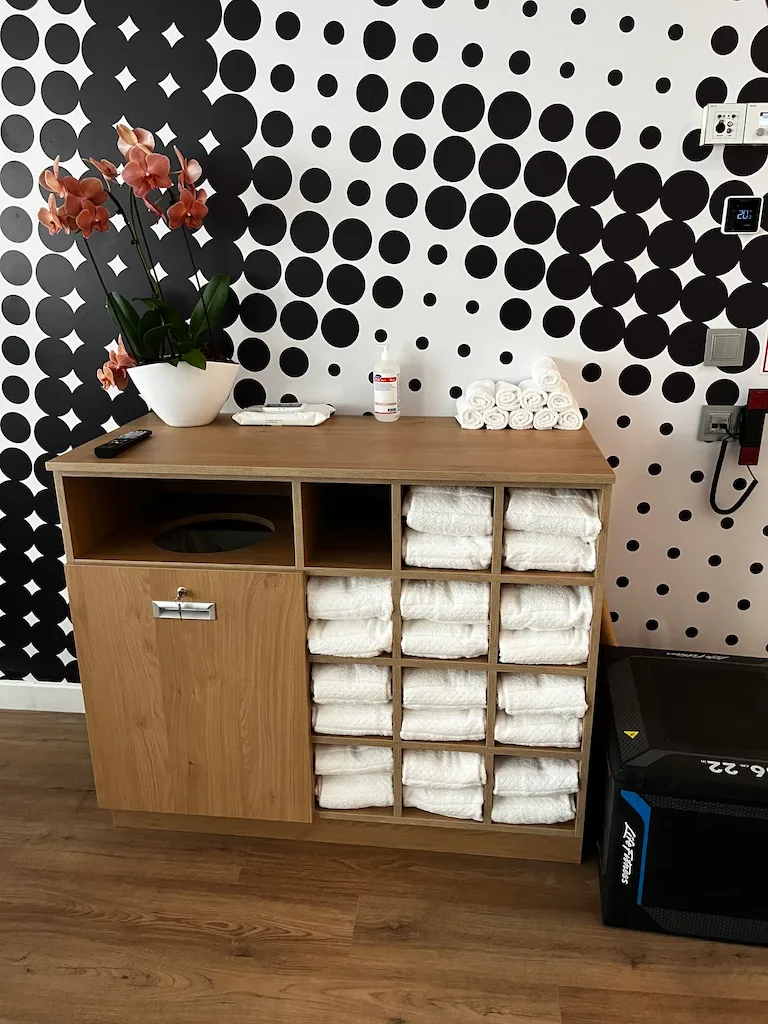 Holzregal mit Handtüchern und Pflanze vor gepunkteter Wand