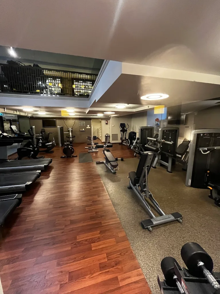 Fitnessraum mit verschiedenen Trainingsgeräten und Holzboden