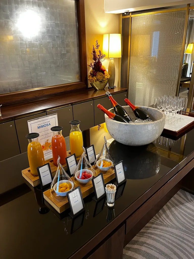 Mimosa-Buffet mit Sektflaschen und Früchten auf schwarzem Tisch