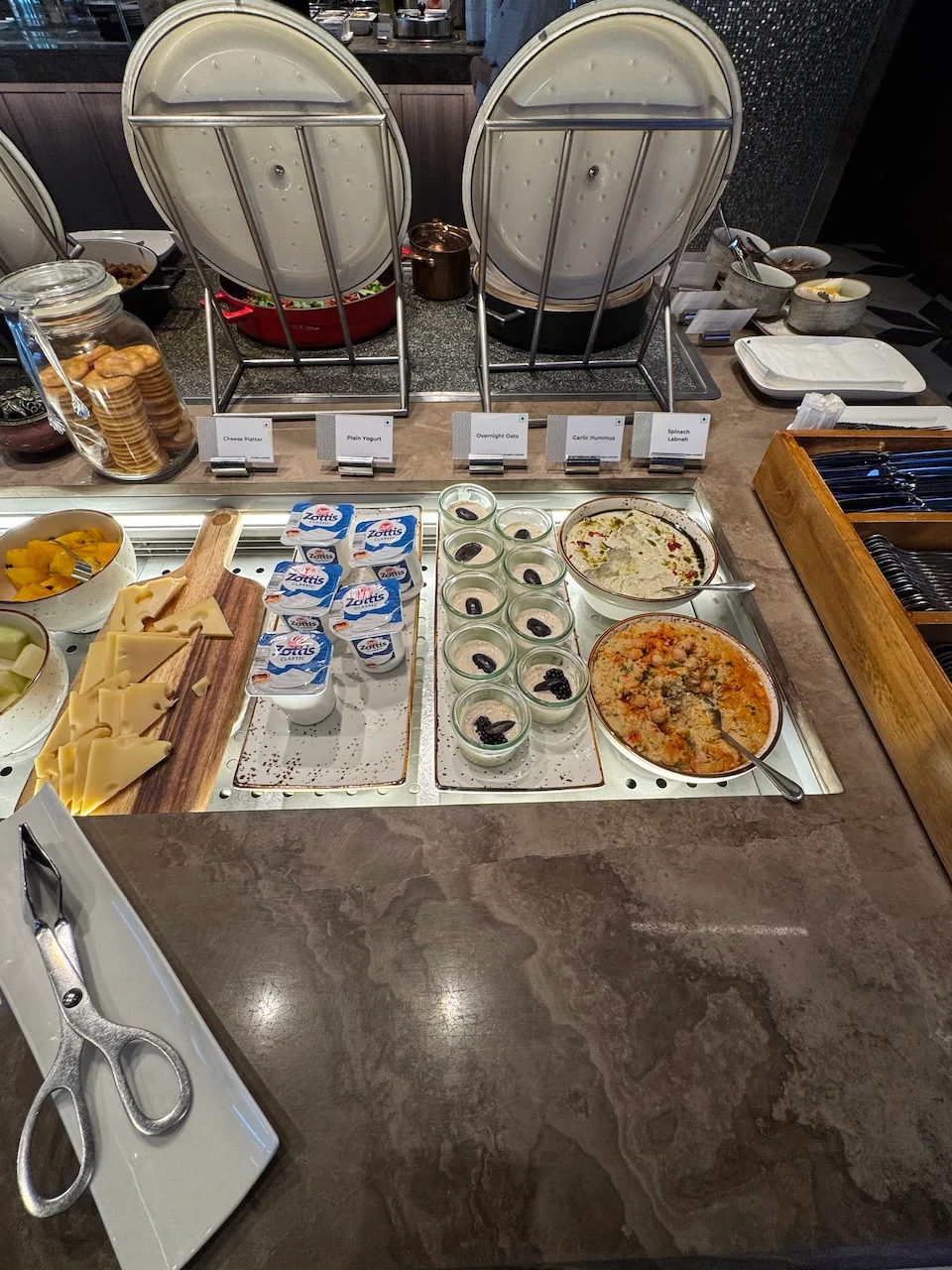 Frühstückstablett mit Käse, Joghurt und Desserts auf einem Frühstückstisch
