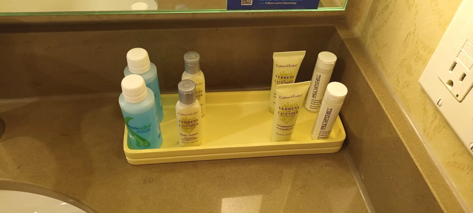 Hotelzimmerservice mit Flüssigseifen und Shampoo auf gelber Tablettplatte