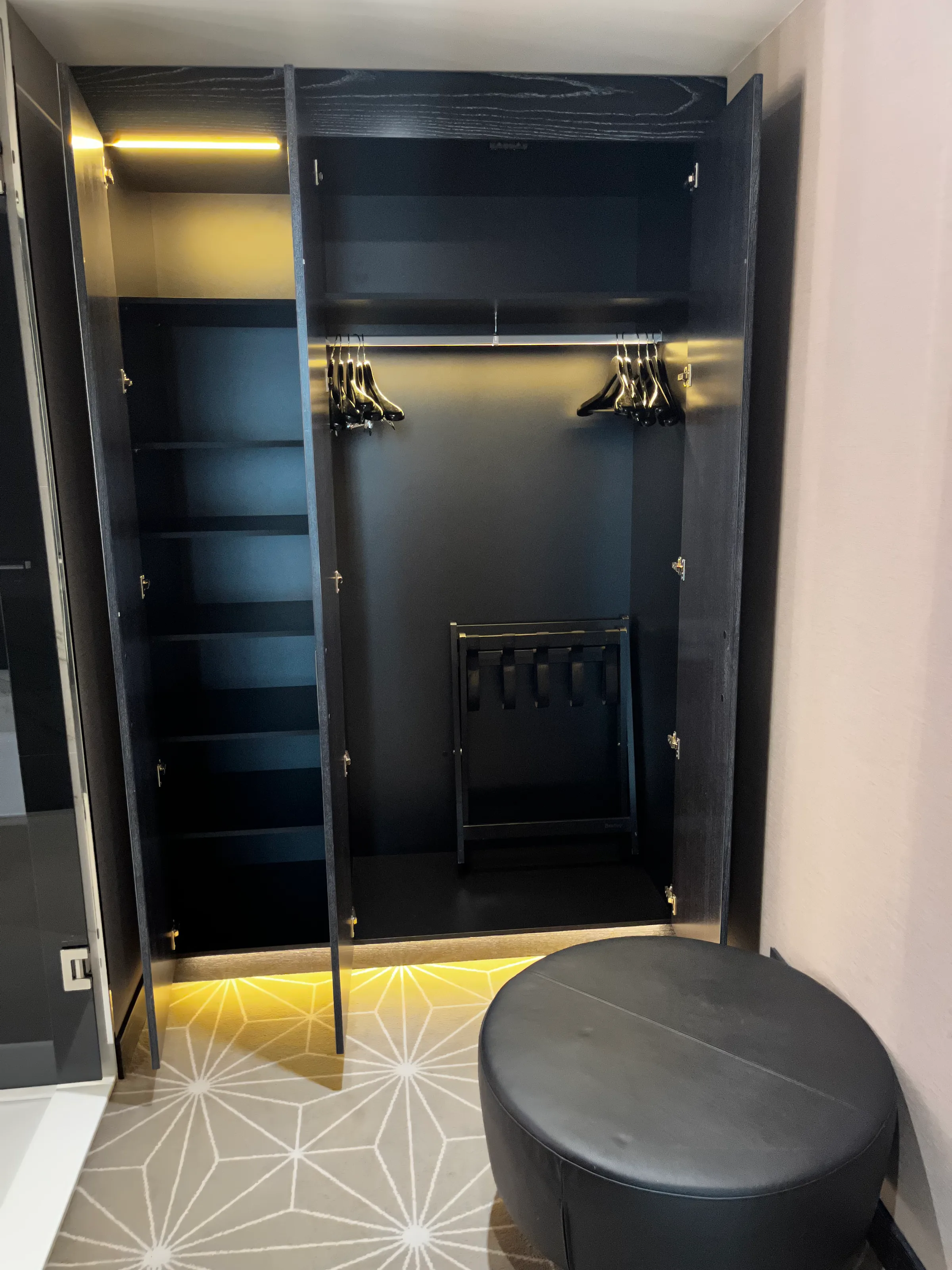 Schwarzer Kleiderschrank mit Haken und Regalen im Hotelzimmer