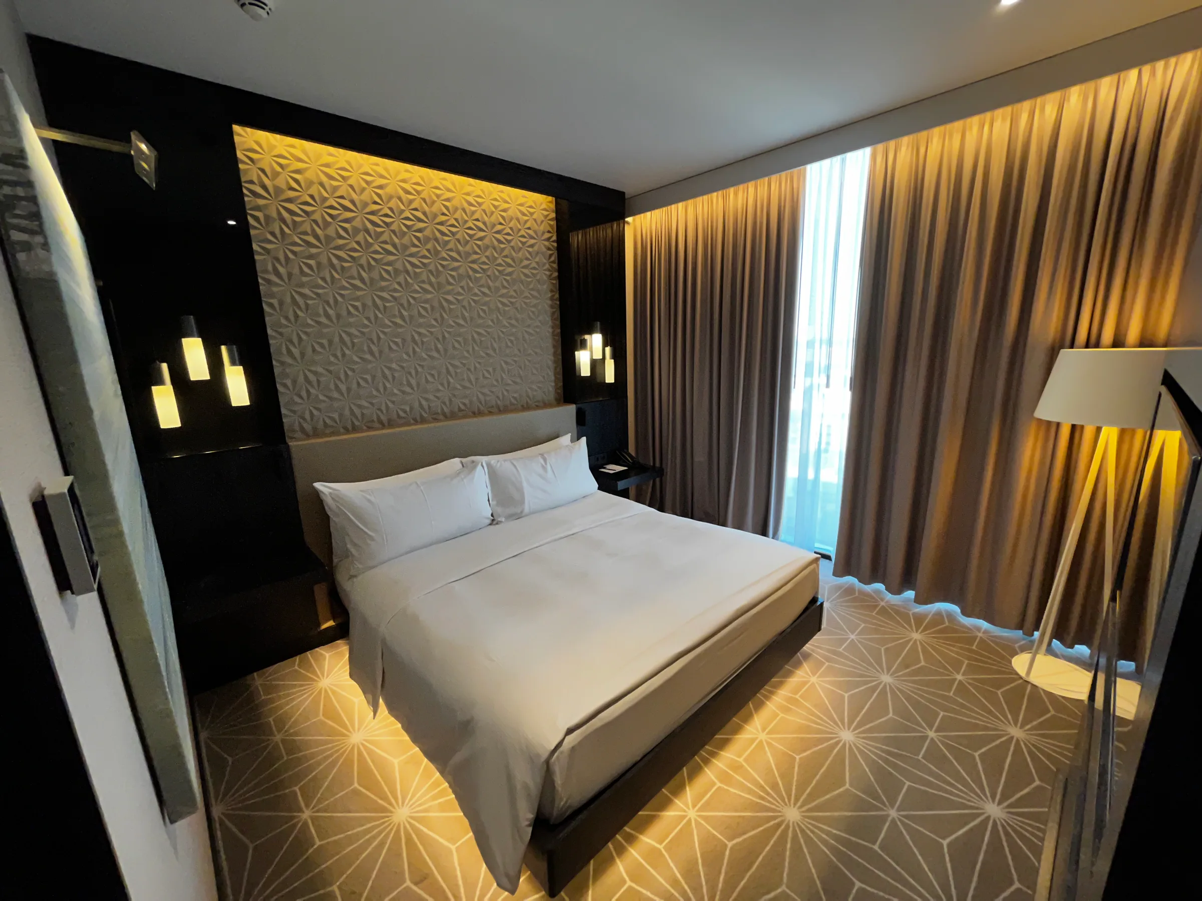 Hotelzimmer mit Doppelbett und grauem Tagesdeckenbesatz
