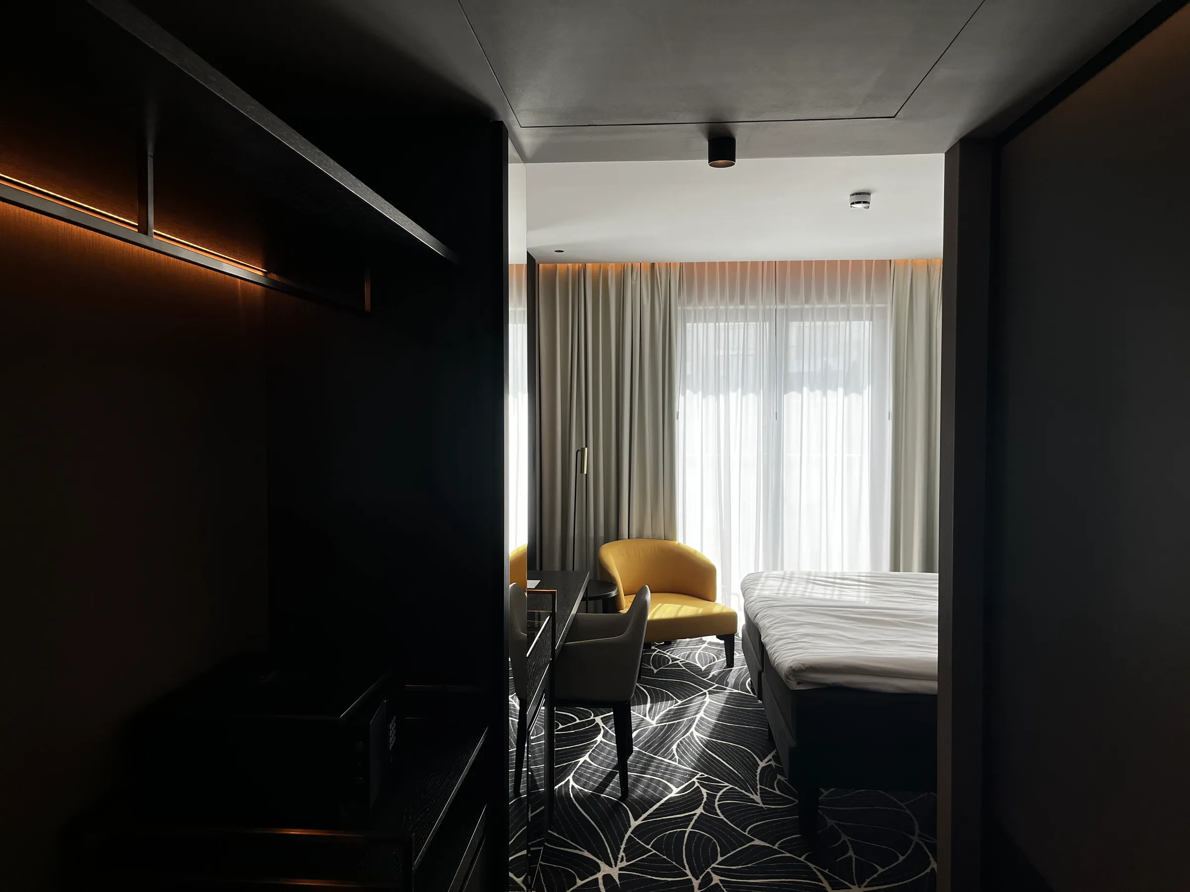 Hotelzimmer mit Doppelbett und gelbem Sessel im modernen Design