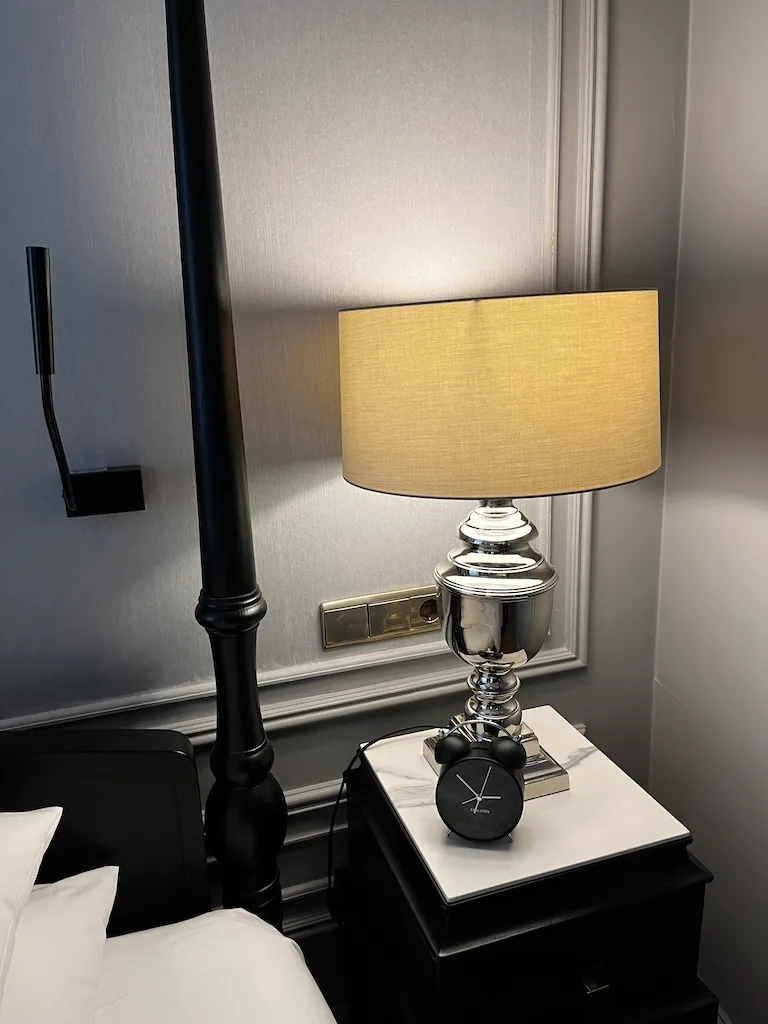 Nachtischlampe mit Uhr auf Nachttisch im Hotelzimmer