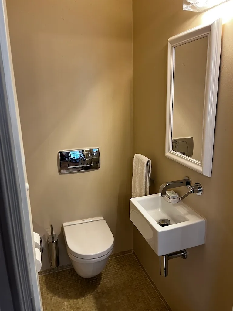 kleines Badezimmer mit Toilette, Waschbecken und Spiegel