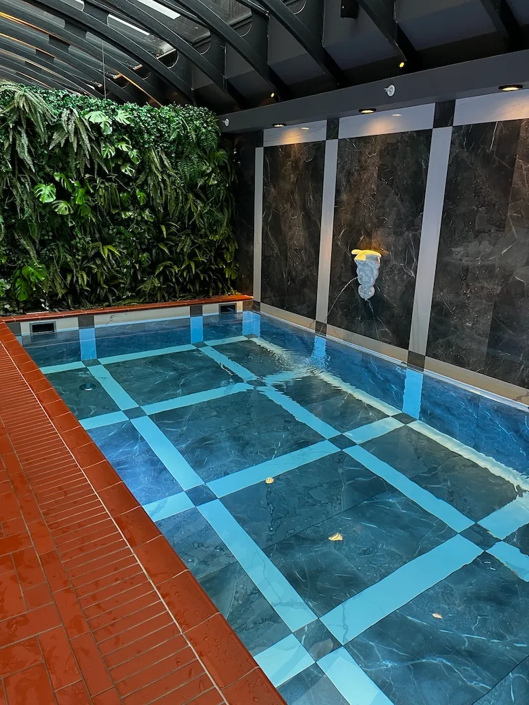 Indoor Pool mit Mosaikfliesen und grüner Wand