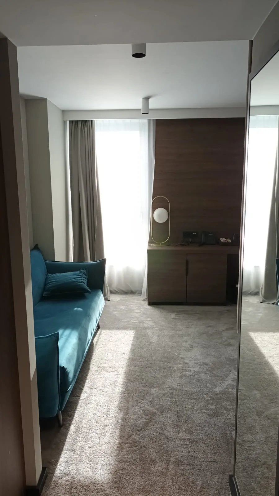 Hotelzimmer mit blauem Sofa und Holzschrank