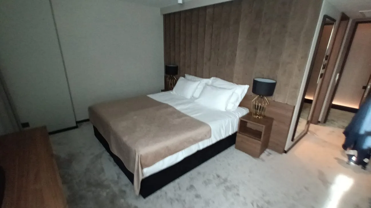 Doppelbett im Hotelzimmer mit grauem Tagesdecken und Nachttischen