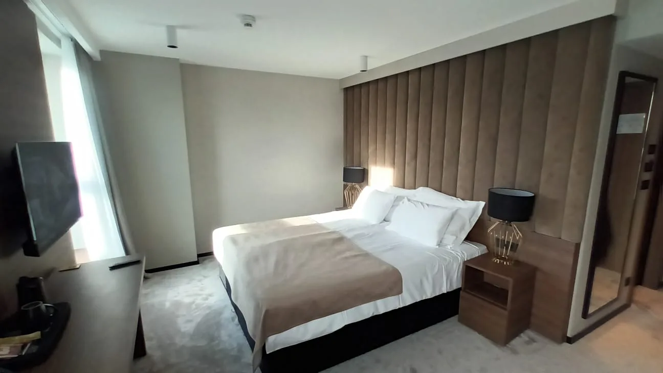 Hotelzimmer mit Doppelbett und Tagesdecke in Grautönen