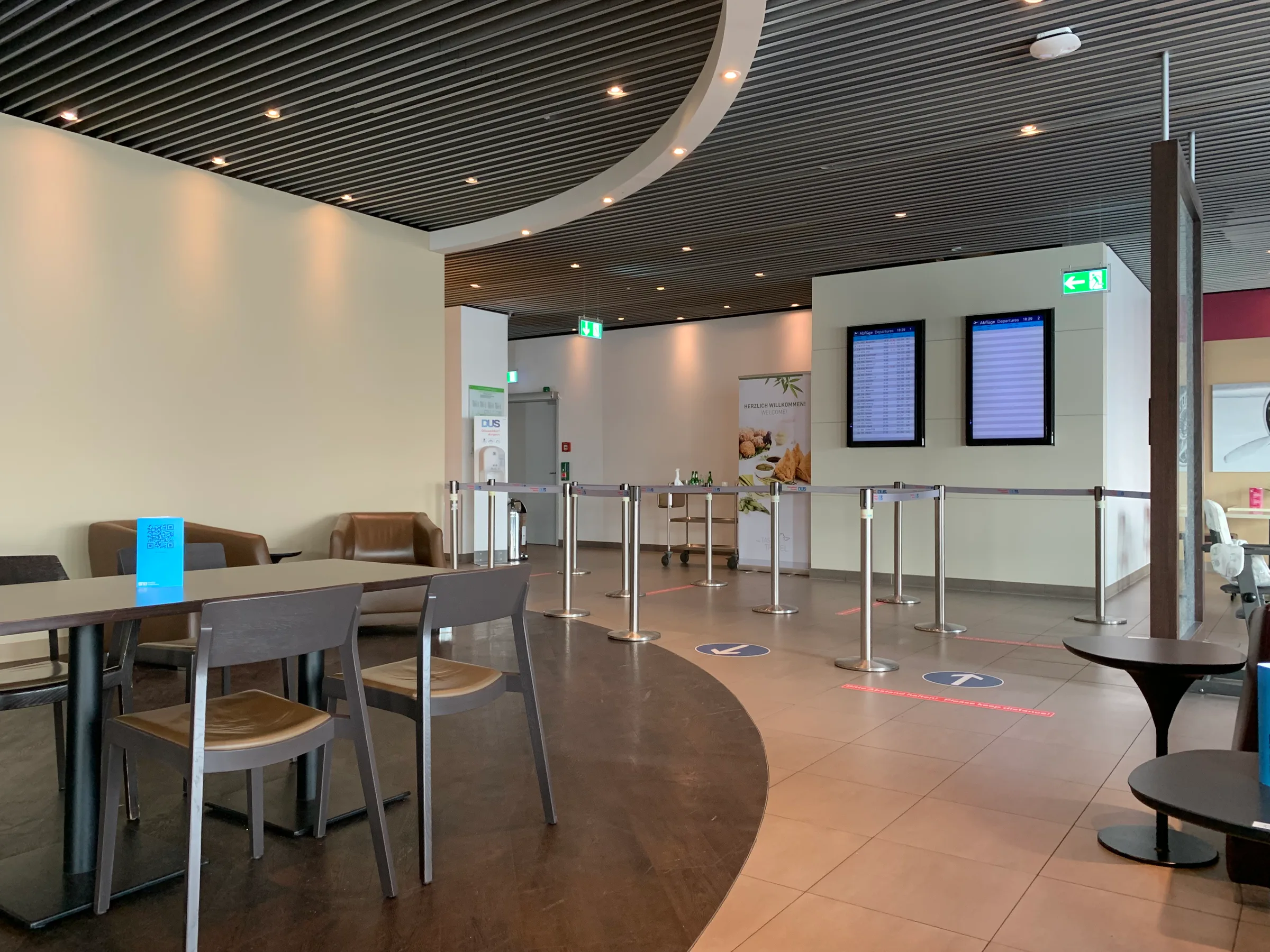 Lounge mit Tischen und Sesseln, Flugplananzeige im Hintergrund