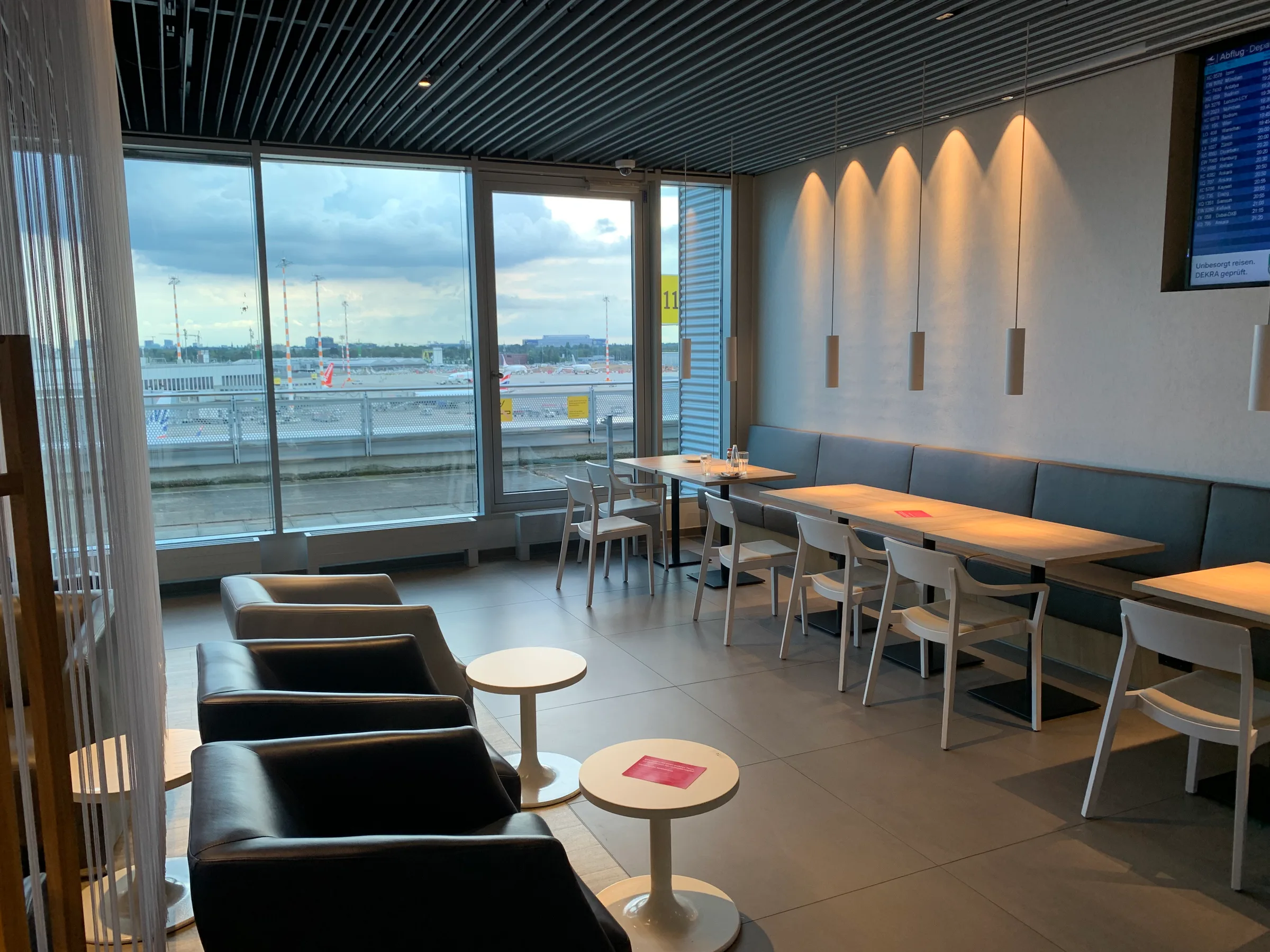 Lounge mit Sitzgelegenheiten und Tischen am Flughafenfenster