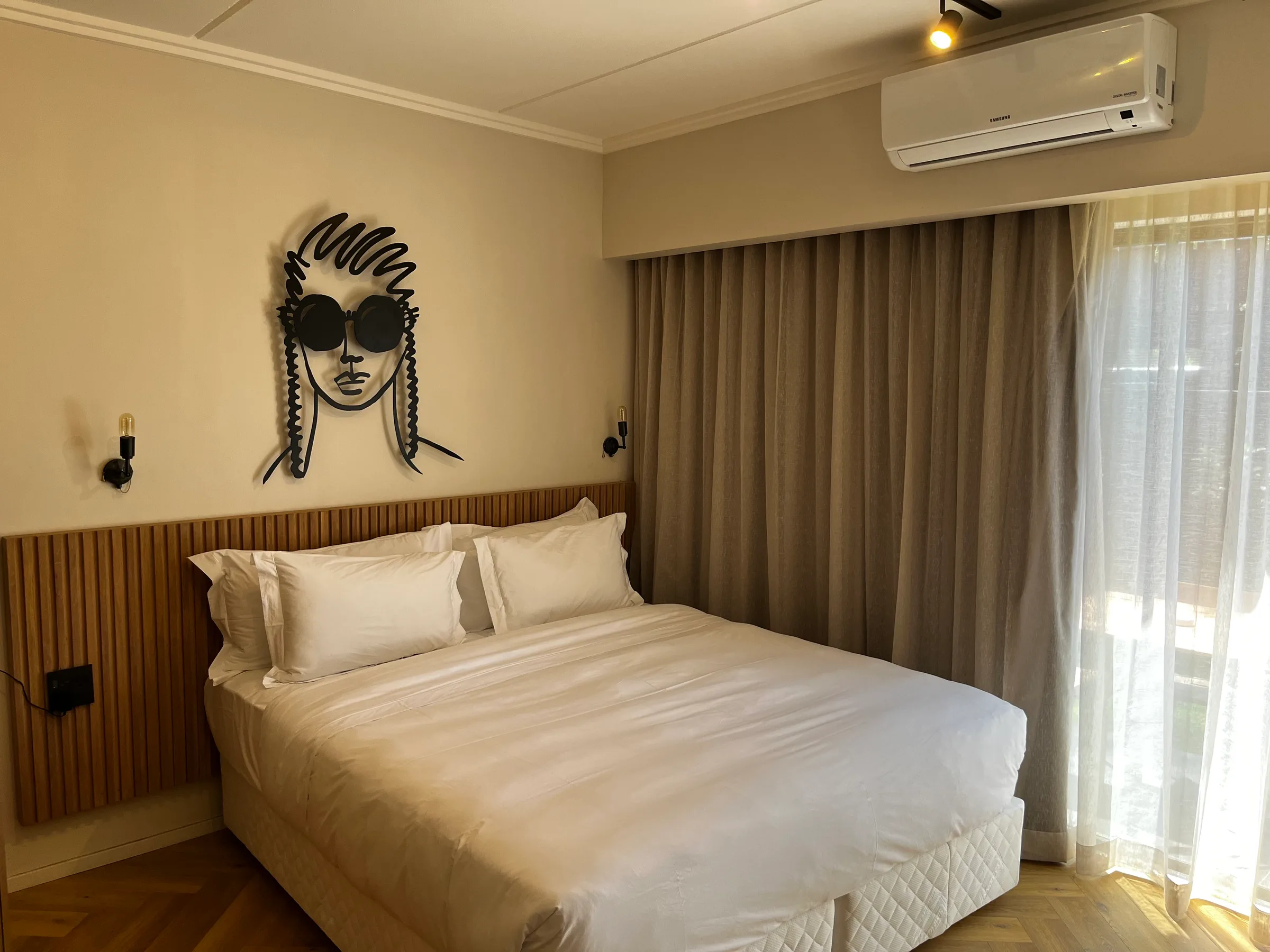 Doppelbett im Hotelzimmer mit grauem Laken und Wanddekoration