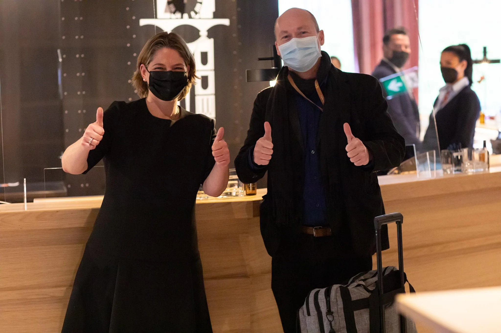 Zwei Personen mit Maske geben Daumen hoch im Hotellobby