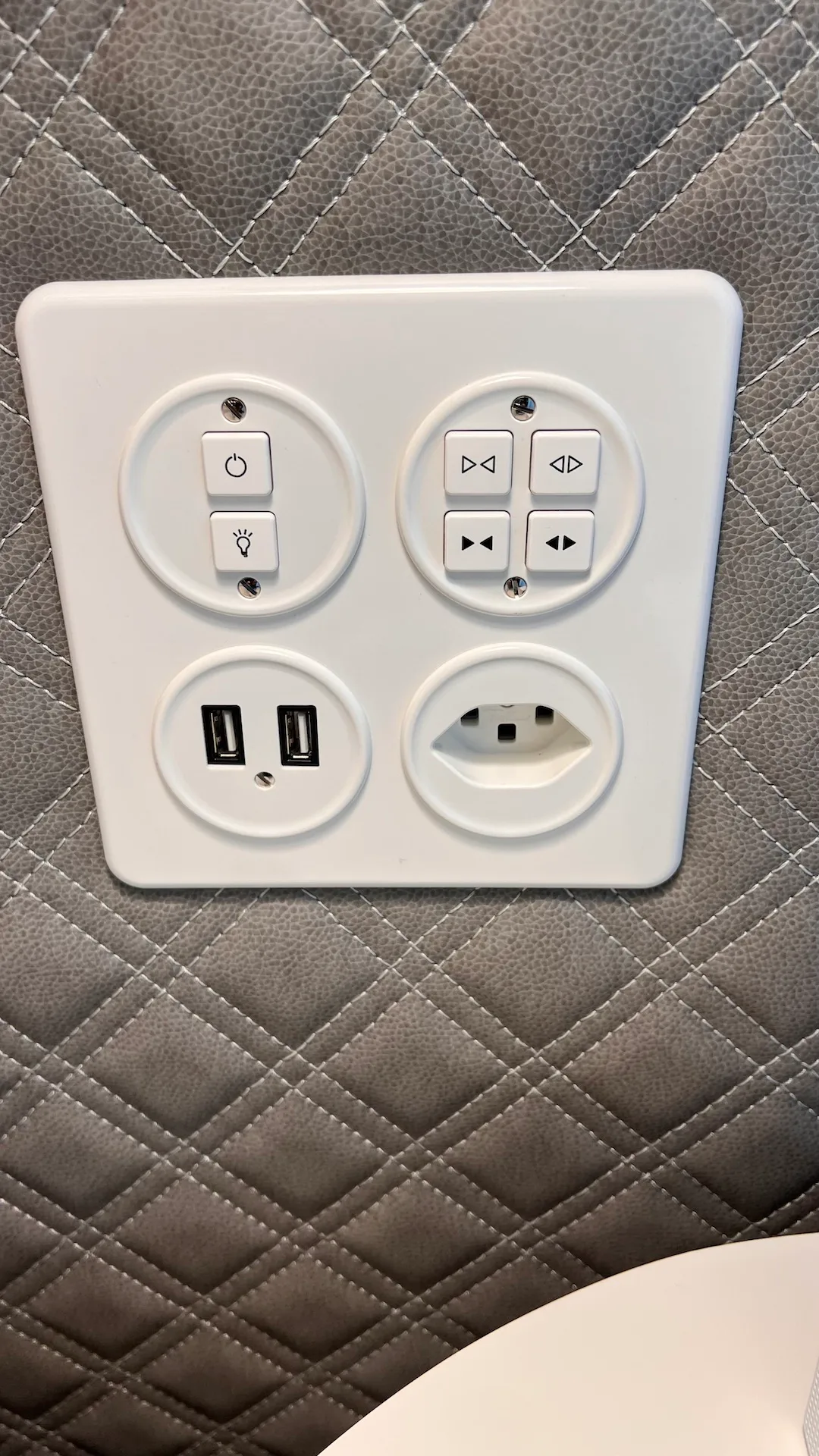 Steckdose mit USB-Anschlüssen und Steuerungselementen auf gepolstertem Hintergrund