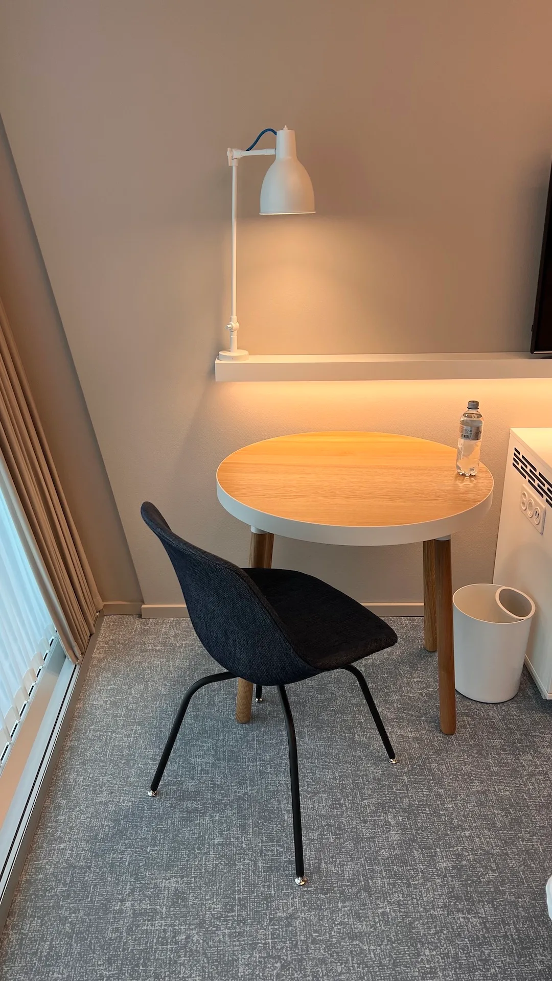 Hotelzimmer mit Tischlampe und Stuhl in neutralen Farben