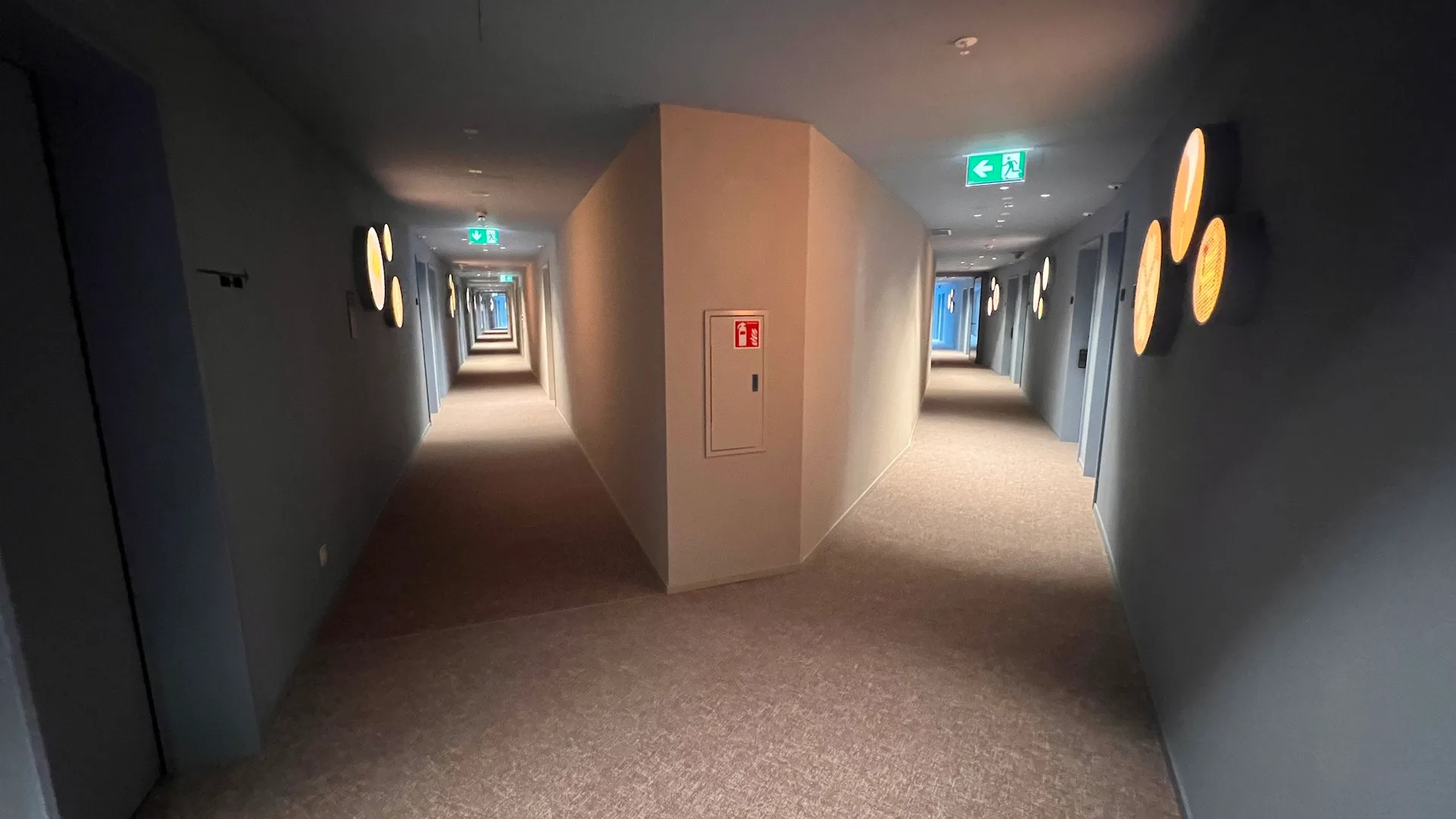 Langer Flur mit Schildern und runden Lichtern an den Wänden