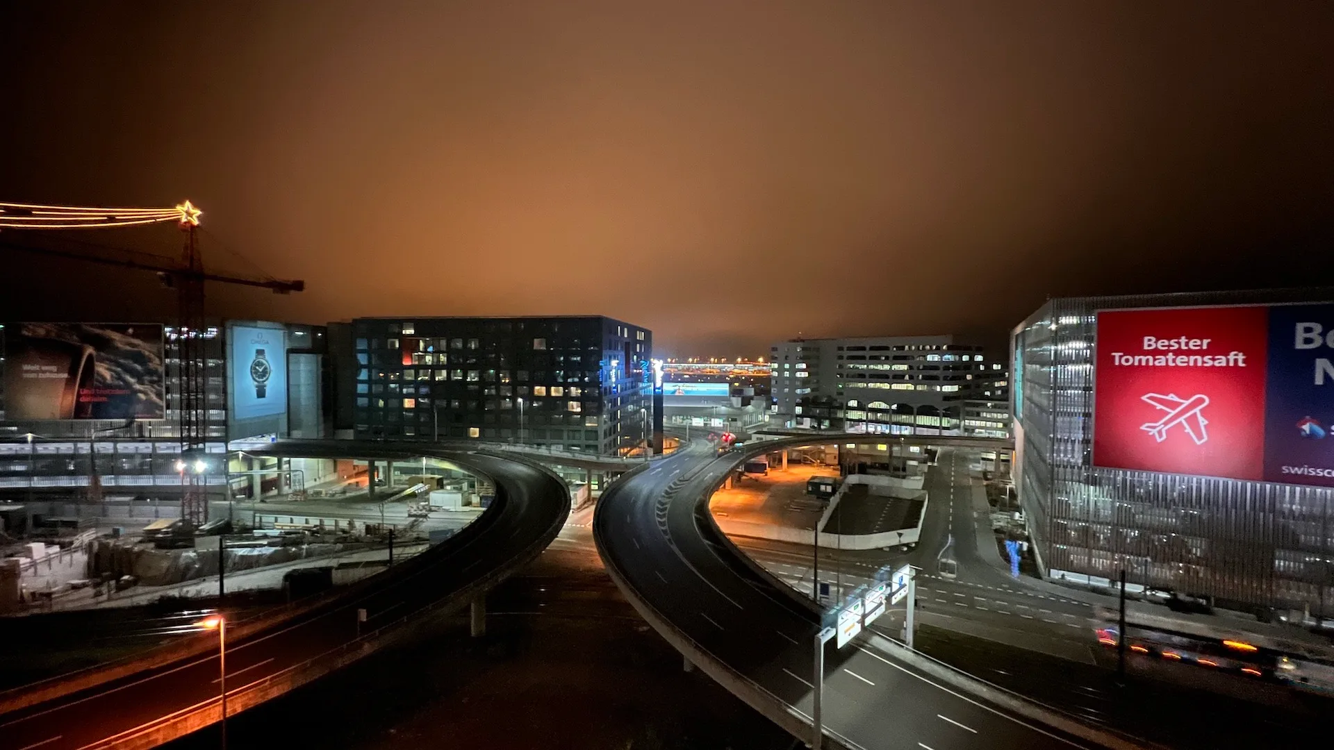 Straßenkreuzung bei Nacht mit Autobahn und Werbetafel