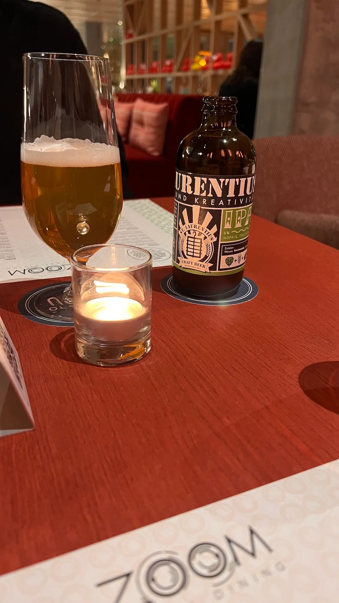 Bierglas mit Schaum und Flasche Craft Beer auf Holztisch