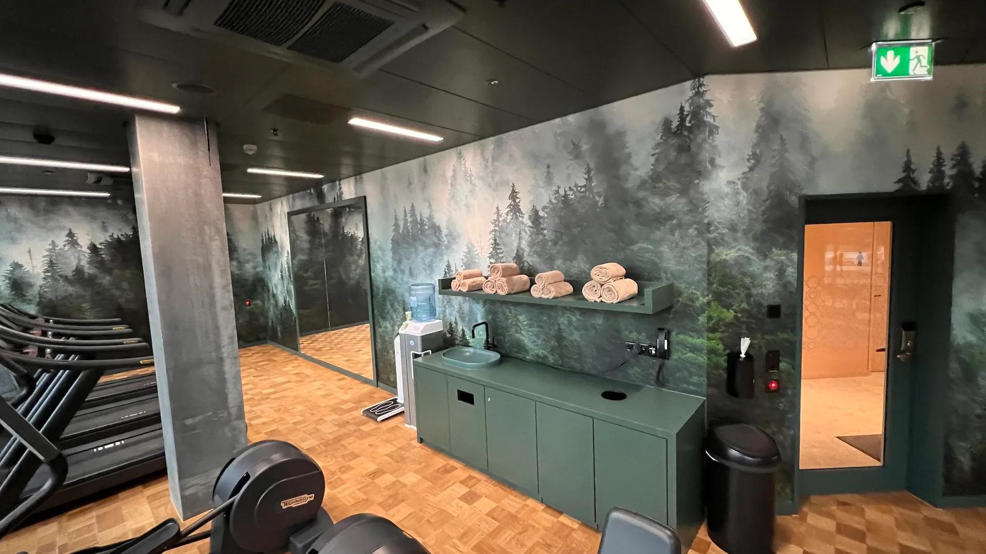 Fitnessbereich mit Waldmotiv an den Wänden