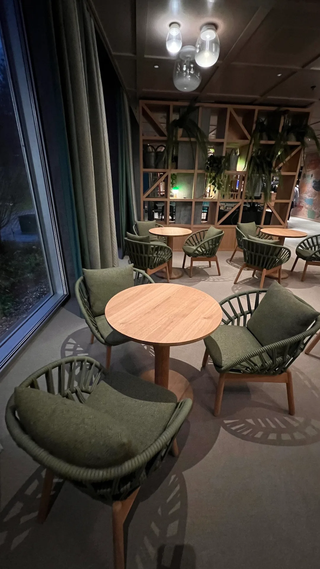 Hotellobby mit runden Tischen und grünen Stühlen