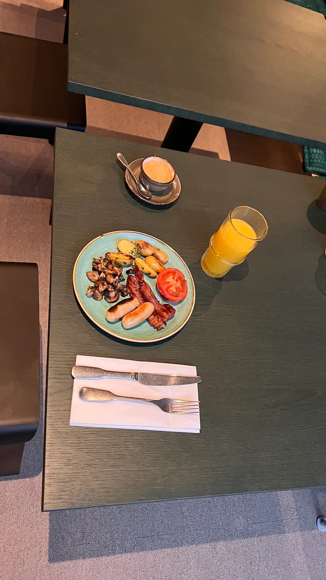 Frühstücksteller mit Würstchen, Tomate, Pilzen und Kartoffeln auf Tisch