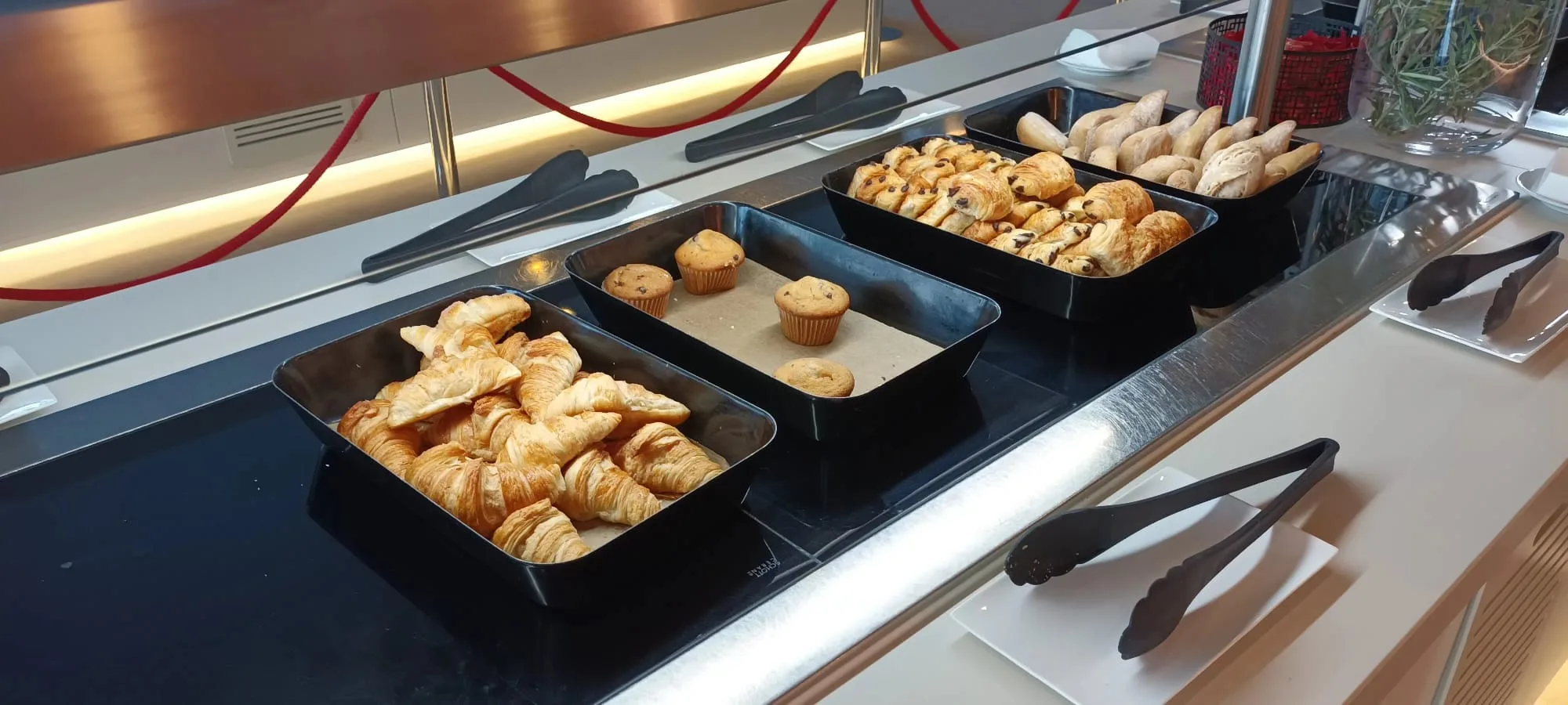 Frühstückstablett mit Croissants, Muffins und Brötchen