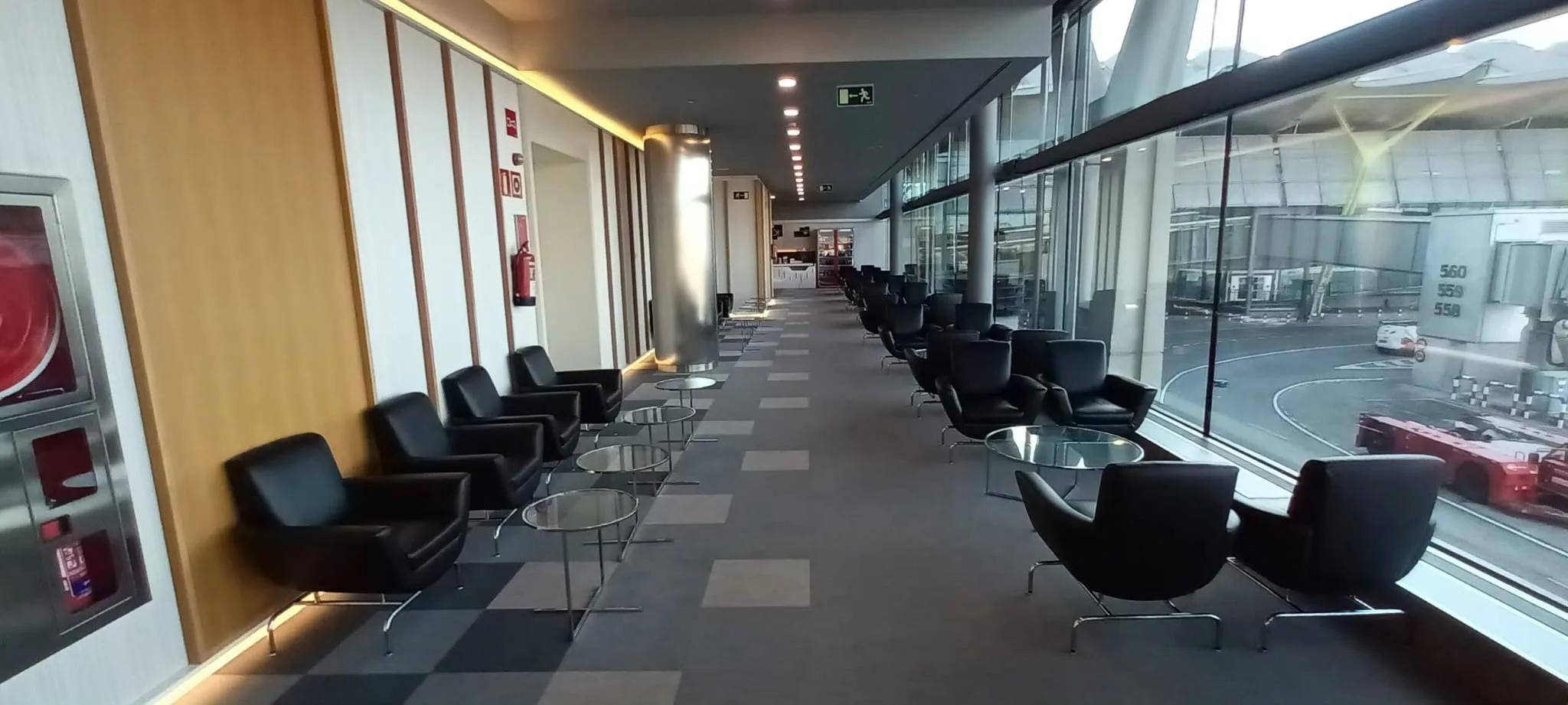 Lounge mit schwarzen Sesseln und Tischen entlang der Fensterfront