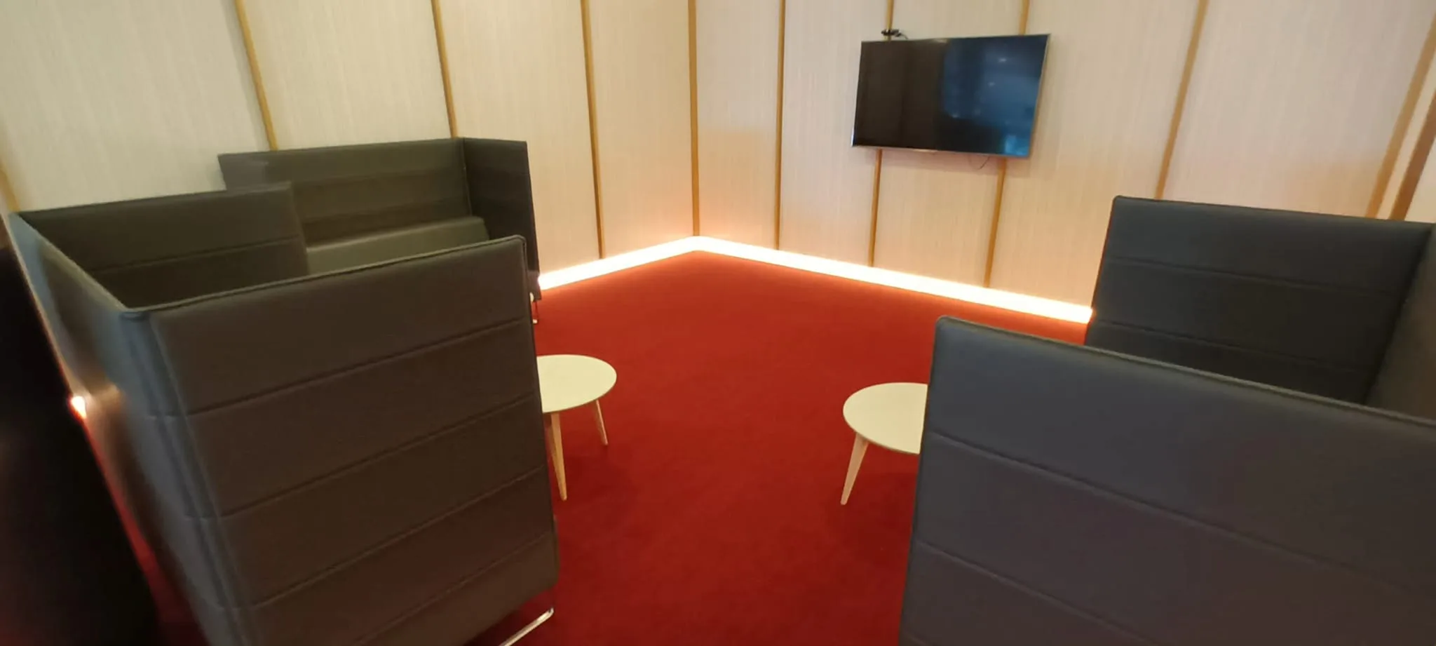 Rote Teppichboden im Loungebereich mit schwarzen Sitzmöbeln und Wandverkleidung