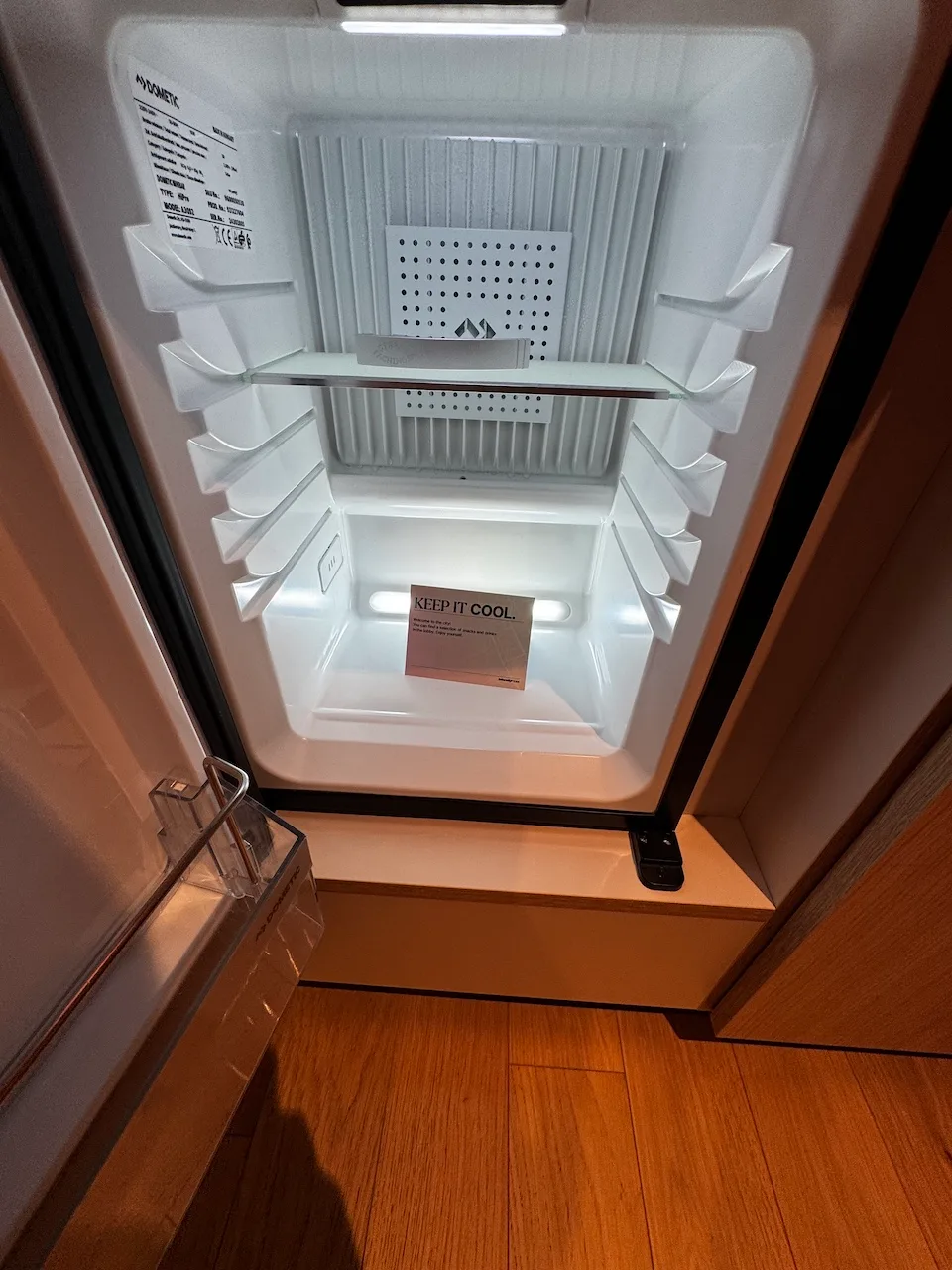 Leerer Kühlschrank mit Regal und Aufschrift 'KEEP IT COOL.'