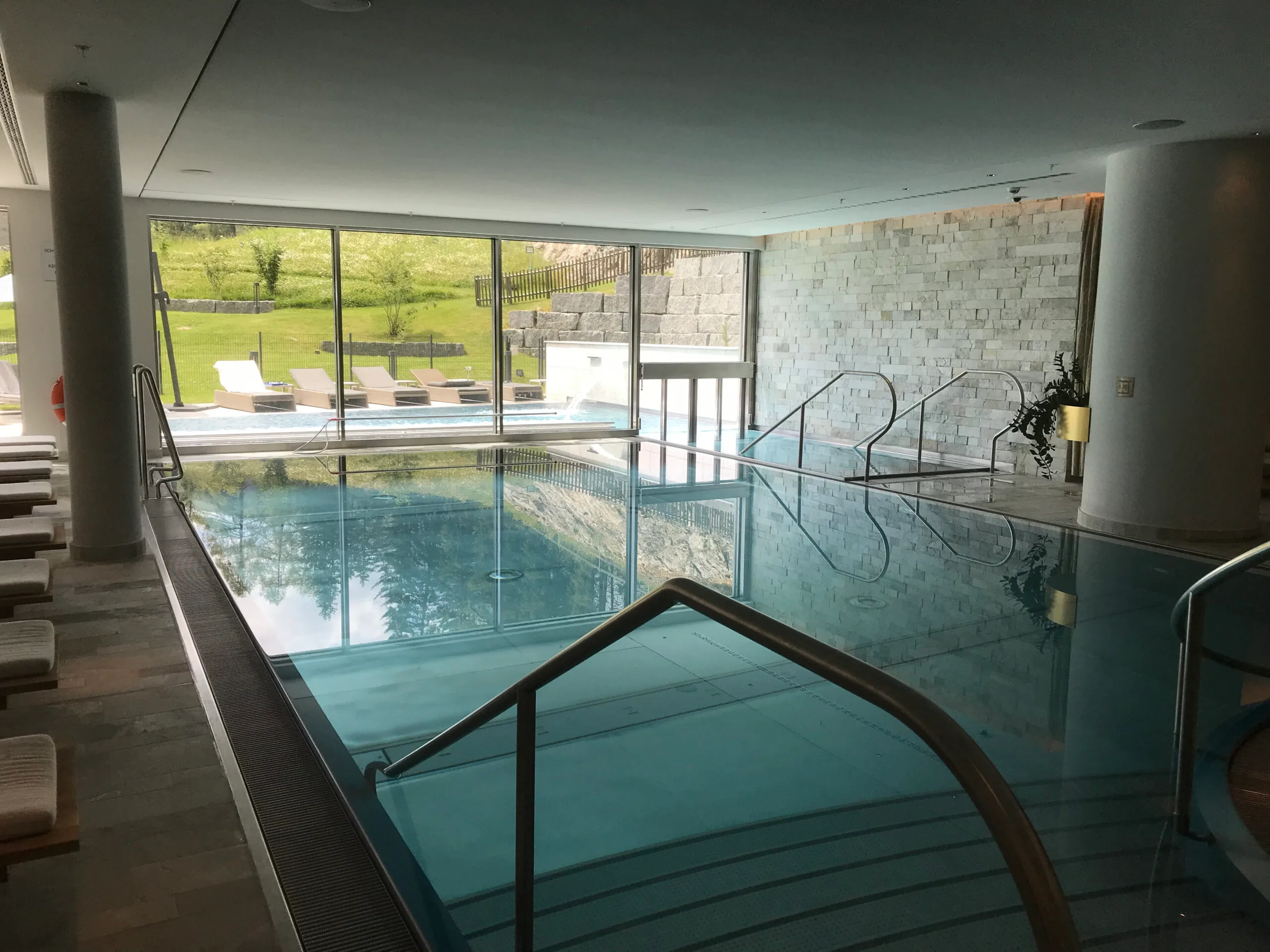 Indoor Pool mit Blick auf Grünfläche und Steingebäude