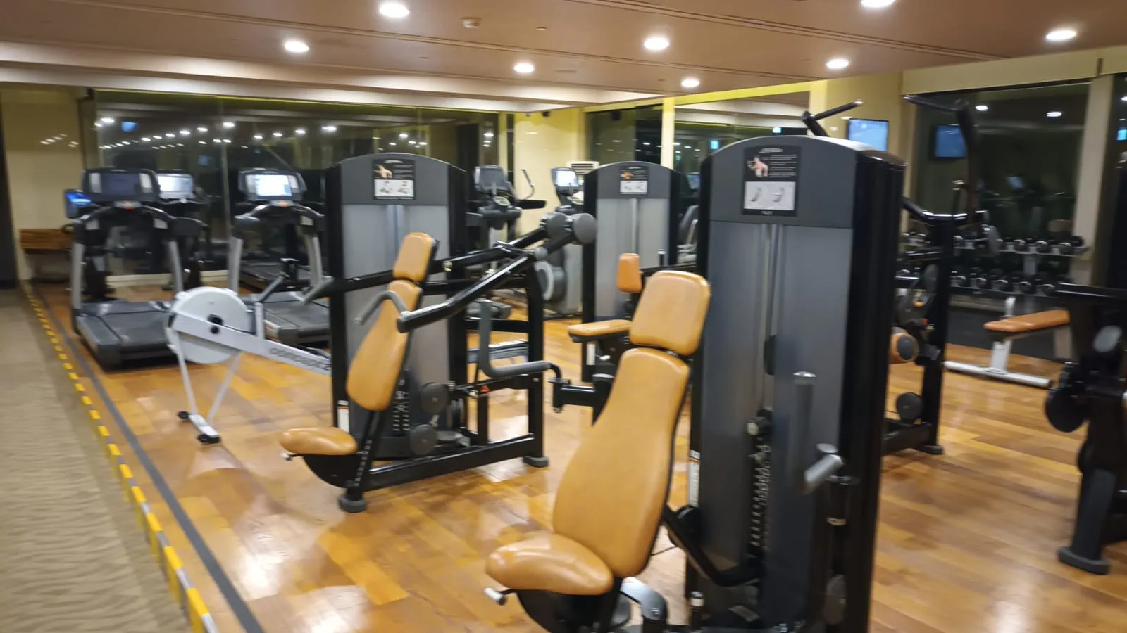 Fitnessraum mit verschiedenen Trainingsgeräten und Spiegeln