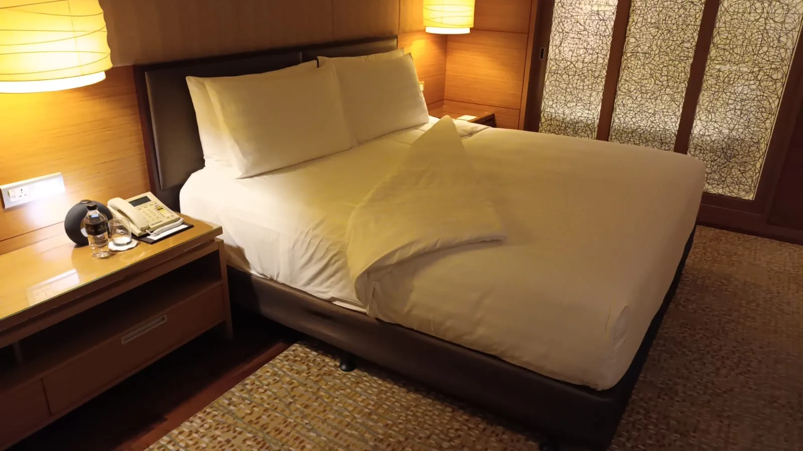 Hotelzimmer mit Doppelbett und Tagesdecke in Grautönen