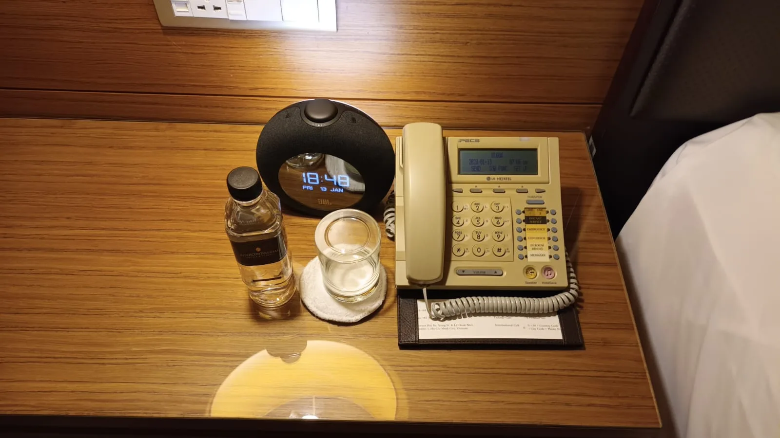 Hotelnachttisch mit Uhr, Telefon und Wasserflasche