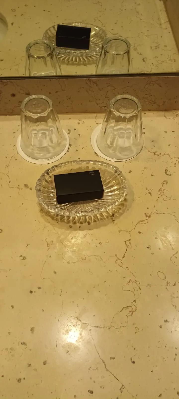 Spiegel mit zwei umgedrehten Gläsern und einem schwarzen Gegenstand auf einer Glasschale