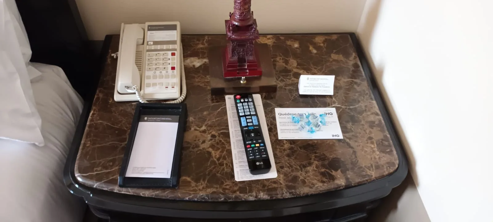 Hotelnachttisch mit Telefon, Fernbedienung und Visitenkarten