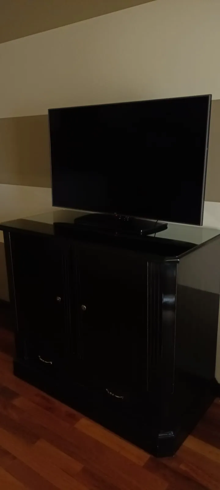 Schwarzer Fernsehschrank mit Flachbildfernseher auf Glasplatte