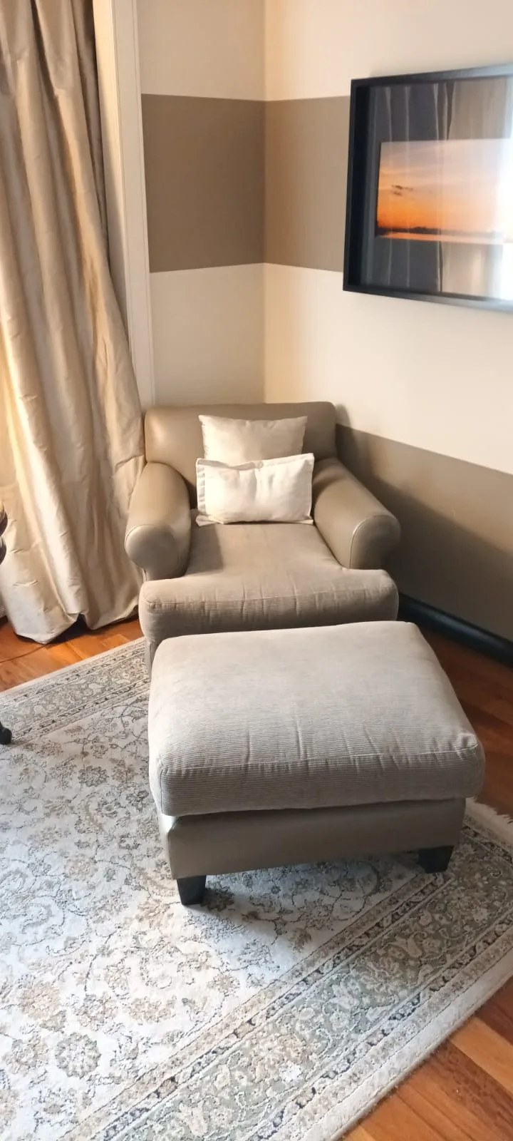 Einzelner Sessel mit Hocker auf Teppich vor Wand mit abgestuften Farben
