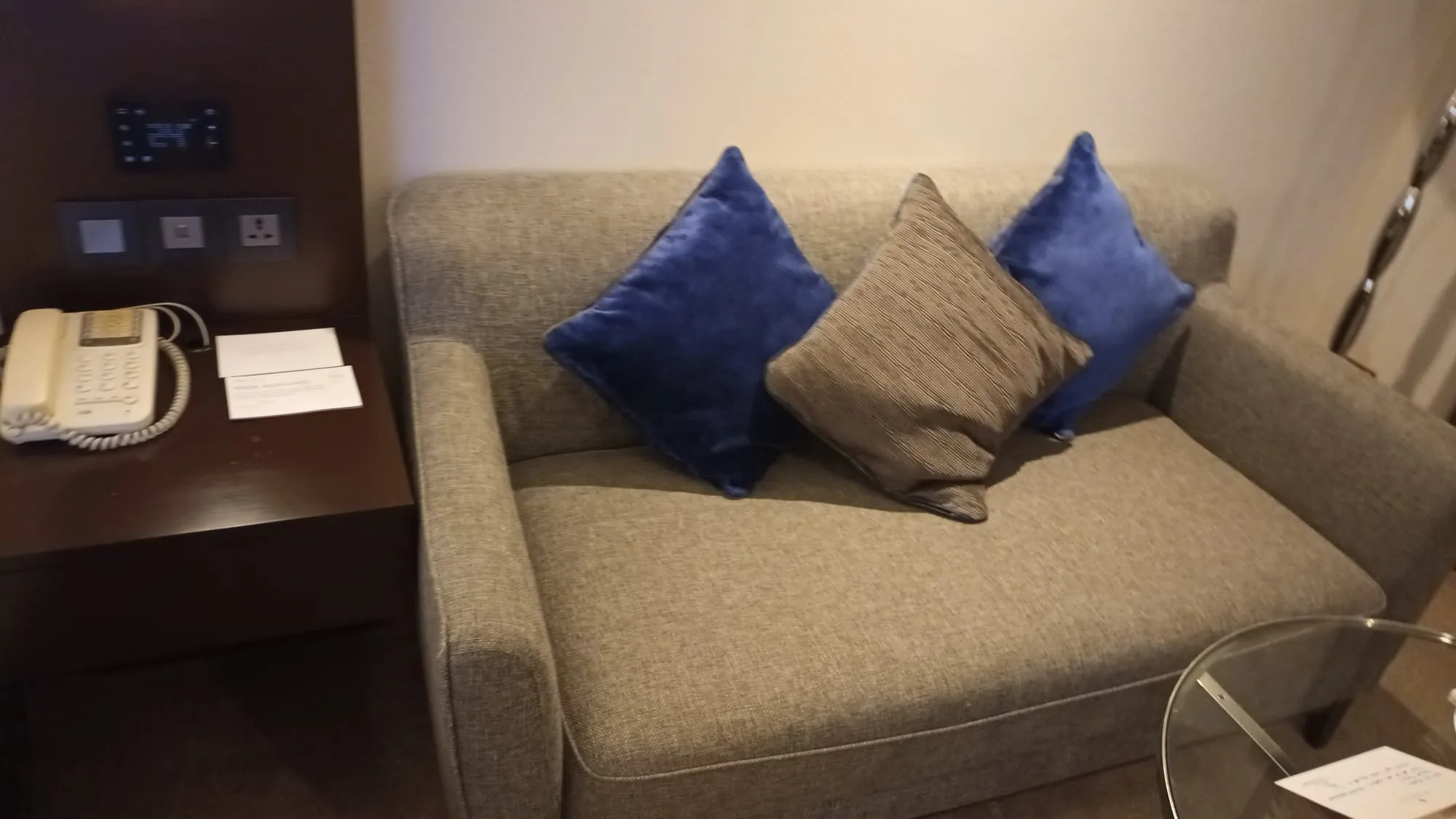 Graues Sofa mit blauen und braunen Kissen in einem Hotelzimmer