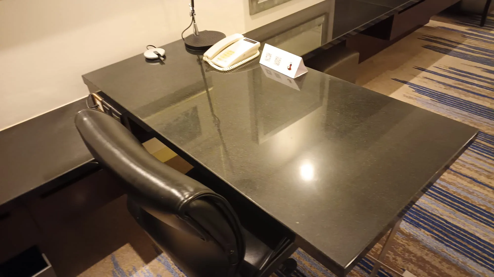 Schreibtisch mit Telefon und Visitenkartenhalter im Hotelzimmer